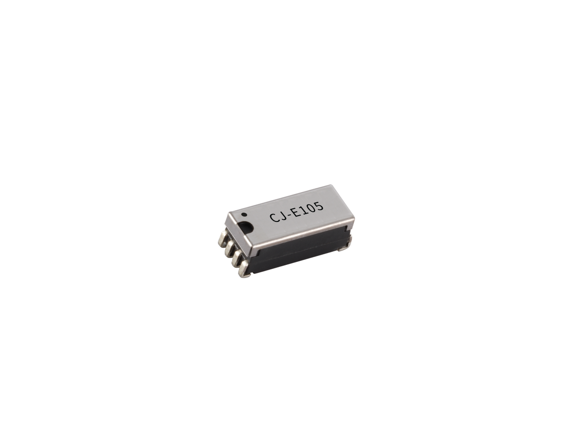 A small, rectangular integrated circuit chip with six metal pins and the code CJ-E105 printed on top, resembling a C Series Reed Relay, isolated on a white background. by Standex Detect