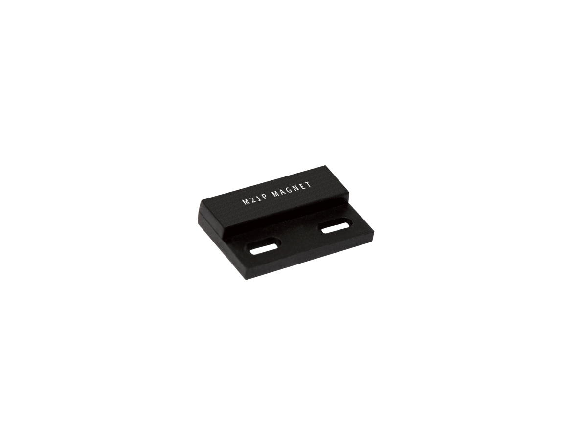 A small black rectangular metal piece labeled “M21P MAGNET” from the M21P Series Magnet line, featuring two elongated mounting holes, shown on a white background. by Standex Detect