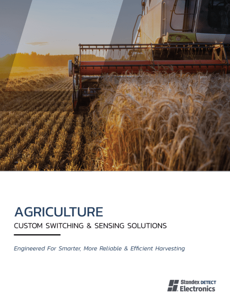 A combine harvester moves through a golden wheat field at sunset. Text below reads: AGRICULTURE & CONSTRUCTION Custom Switching & Sensing Solutions. Engineered for smarter, more reliable & efficient harvesting. Standex Electronics logo. by Standex Detect