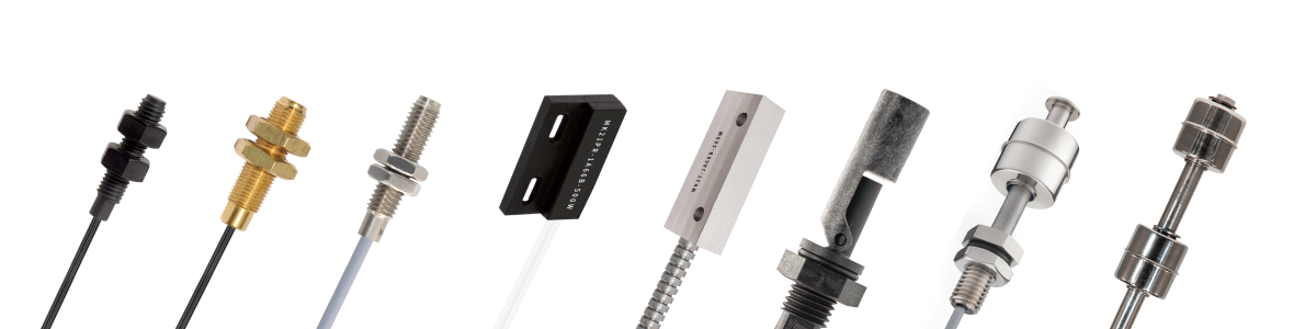 A row of various industrial sensors and metal components, including threaded and cylindrical shapes, reed switches, and float switches—all showcasing the sensing technologies driving industry—are arranged upright on a white background. by Standex Detect