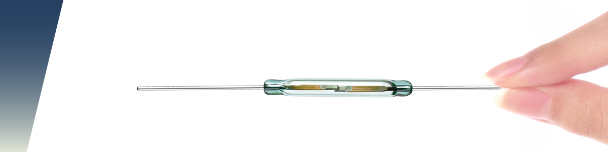 A hand holds a small glass reed switch, commonly used in liquid level sensors and floats, with metal wires extending from both ends, set against a white background with a blue gradient on the left. by Standex Detect