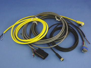 A bundle of various cables in yellow, black, and gray, each with different connectors—some designed for sensors to measure speed—arranged on a blue background. by Standex Detect
