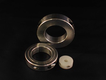 Three round mechanical components on a black background: two metal rings with holes and set screws—often used in conjunction with sensors to measure speed—and one smaller white plastic ring with a hole. by Standex Detect