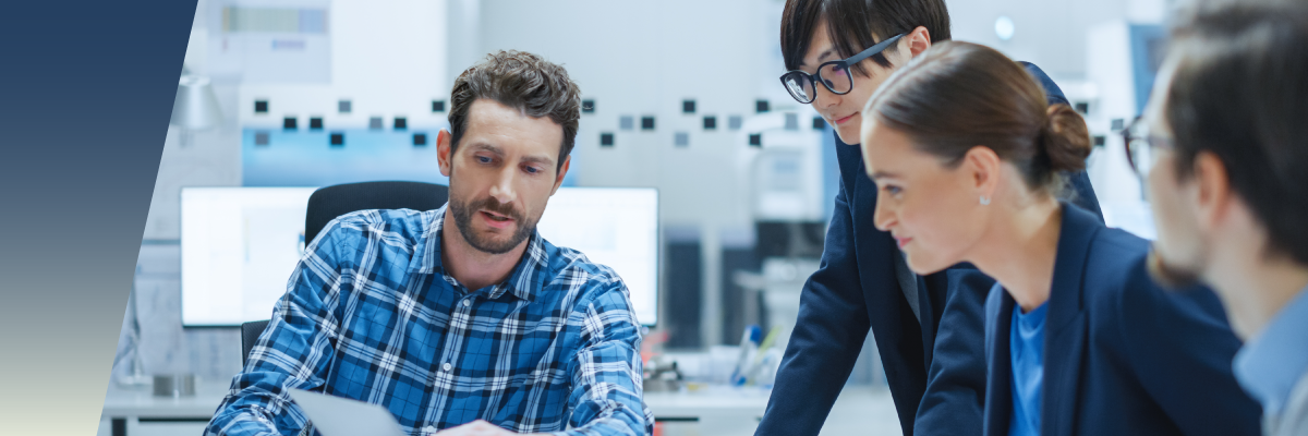 Three colleagues collaborate at a desk, reviewing a document on the system performance impact of a relay. by Standex Detect